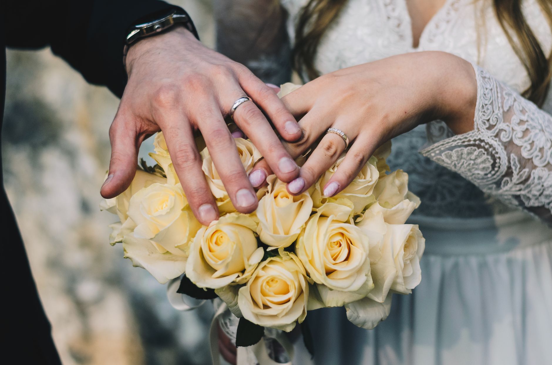 Alliances tenues par un couple entouré de fleurs