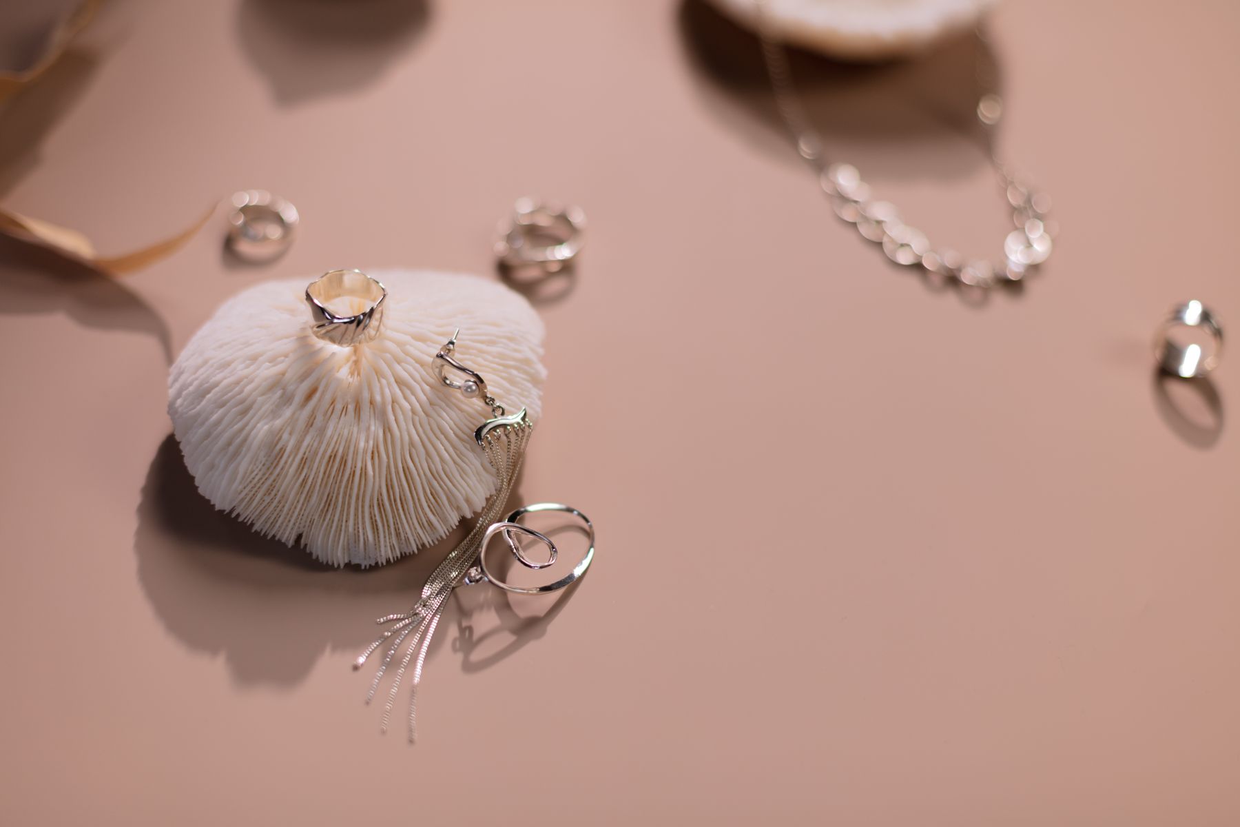 Bagues et collier en argent sur fond rose