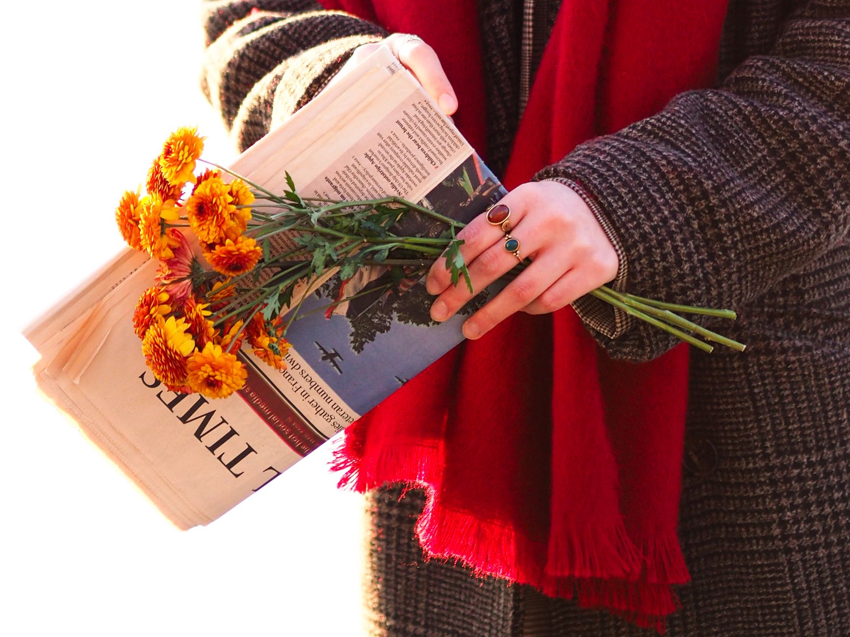 Écharpe rouge à franges tenue avec un bouquet de fleurs