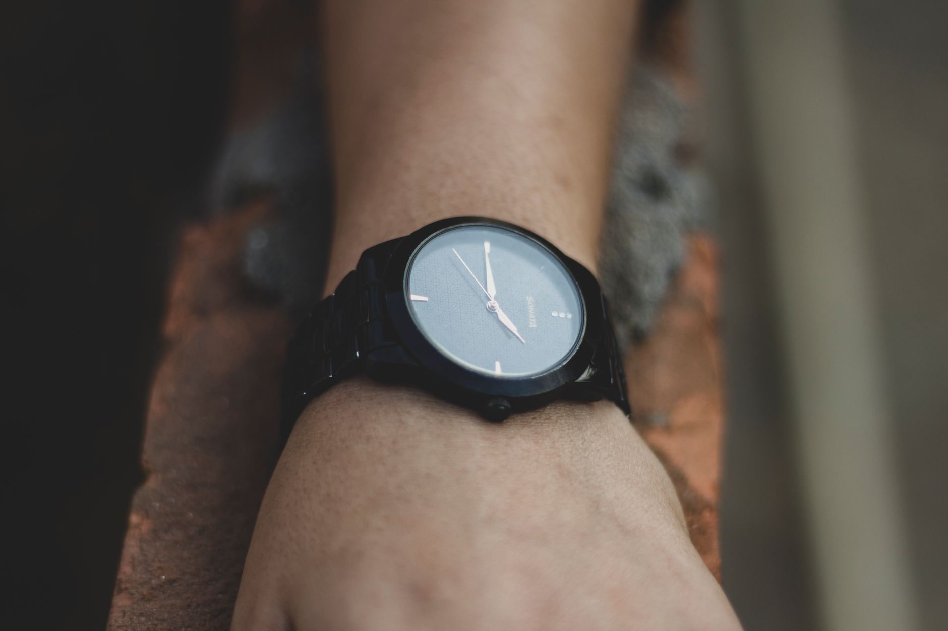 Montre analogique noire portée au poignet