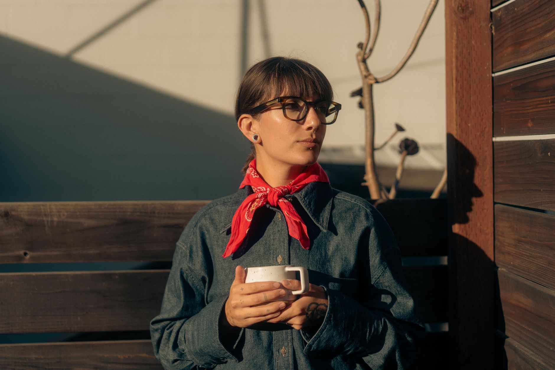Femme au bandana rouge noué dans les cheveux, tasse de café à la main