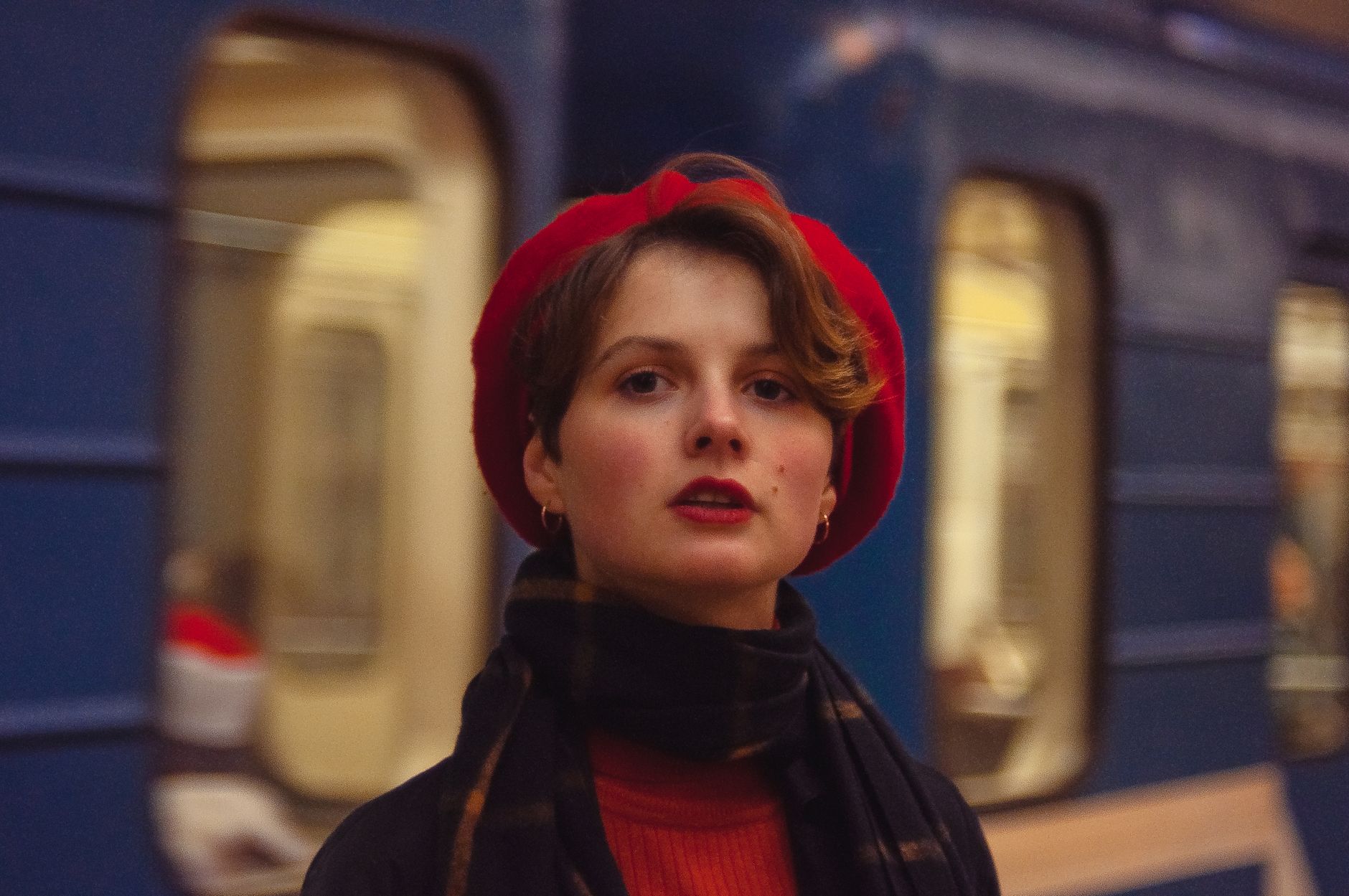 Femme coiffée d’un béret rouge devant une rame de métro