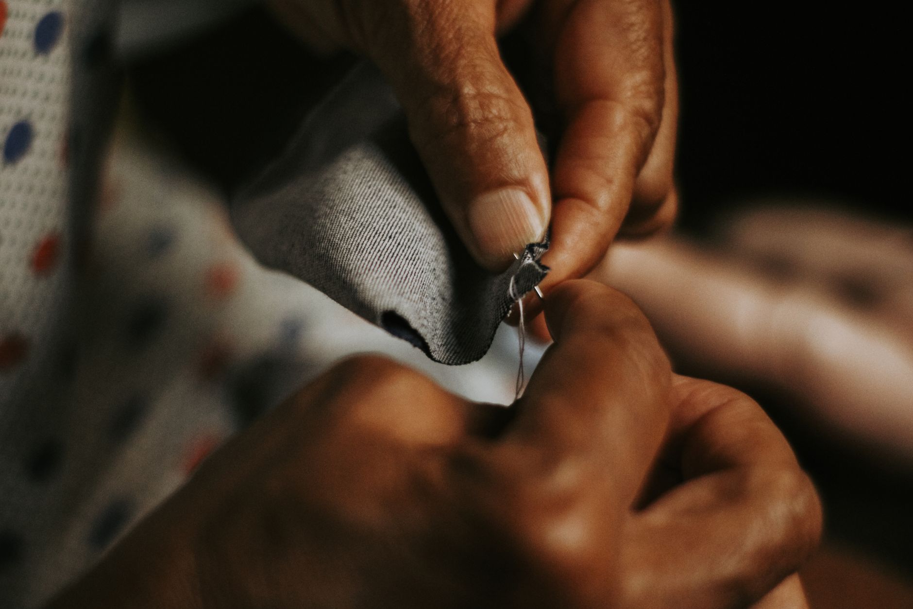 Mains qui cousent un tissu gris avec fil et aiguille
