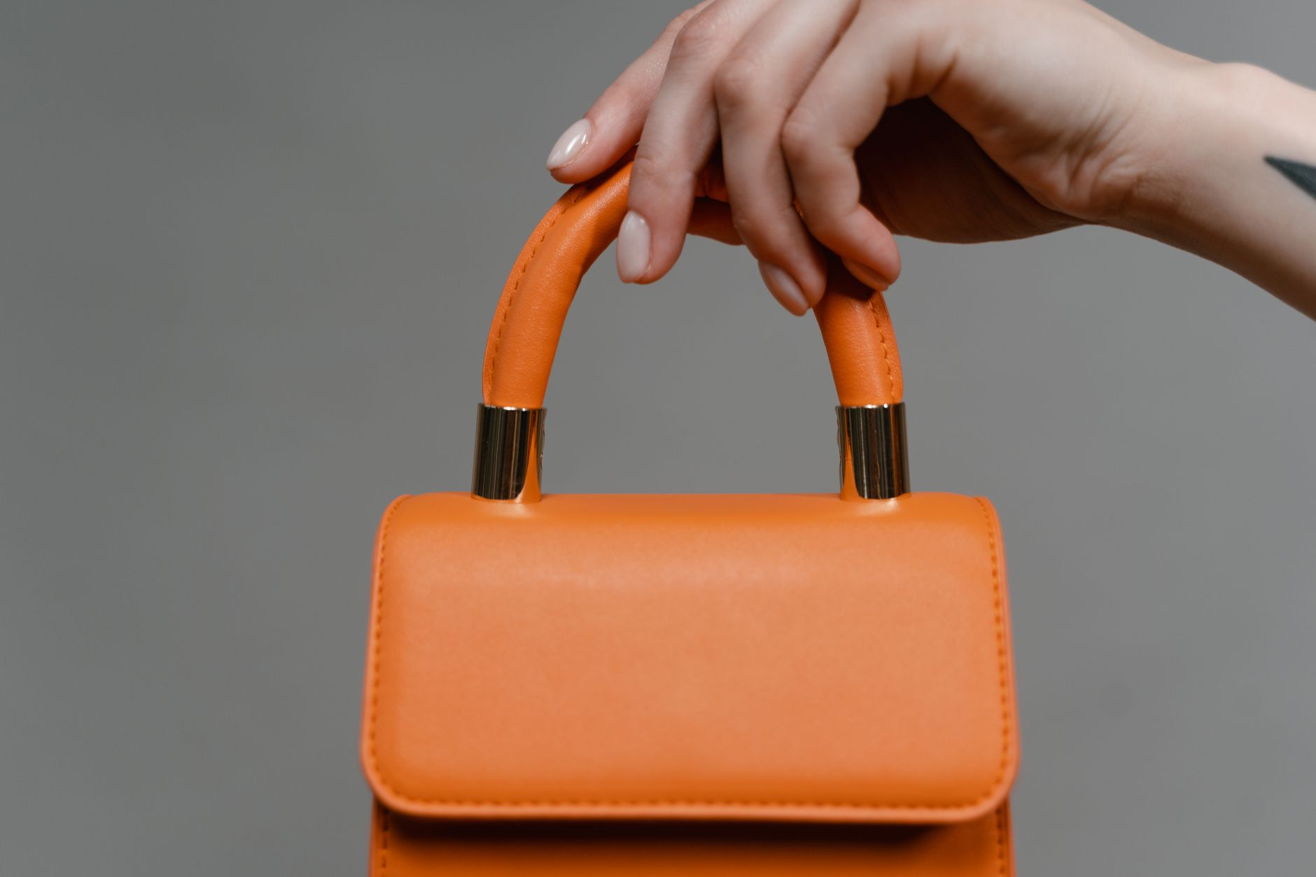 Main qui tient un sac à main orange