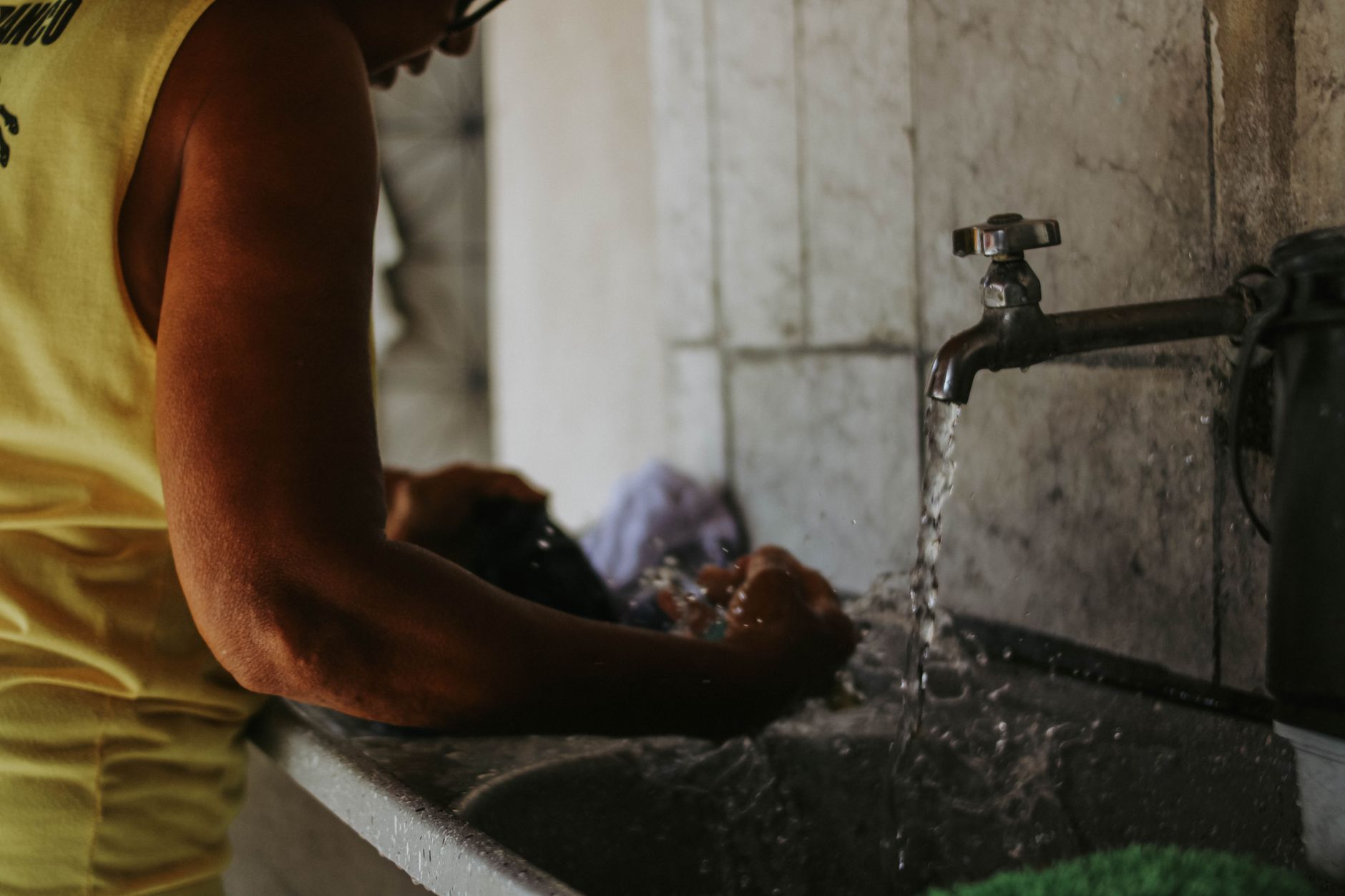 Vêtement lavé à la main dans un évier sous l’eau courante
