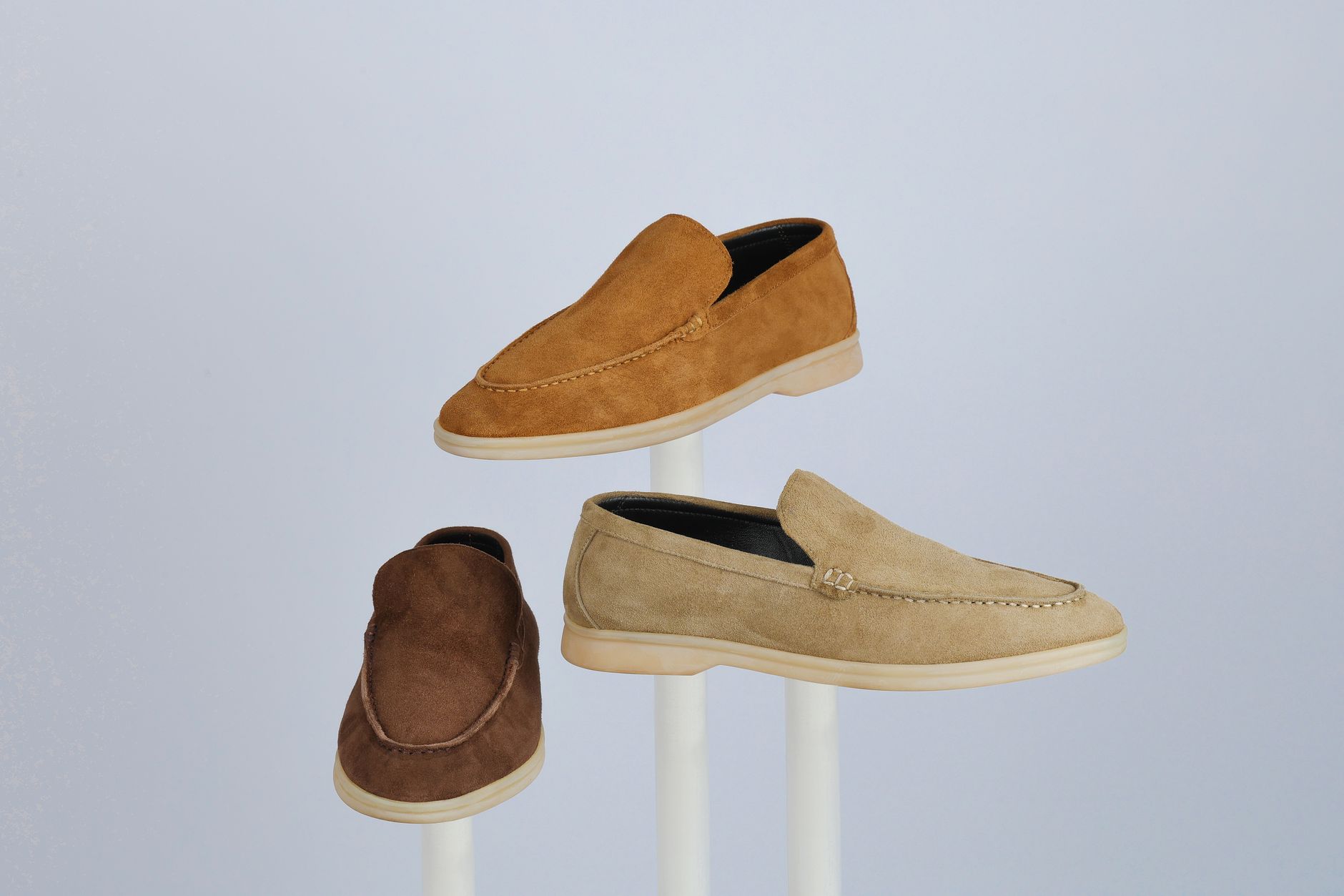 Trois mocassins en daim présentés sur des supports