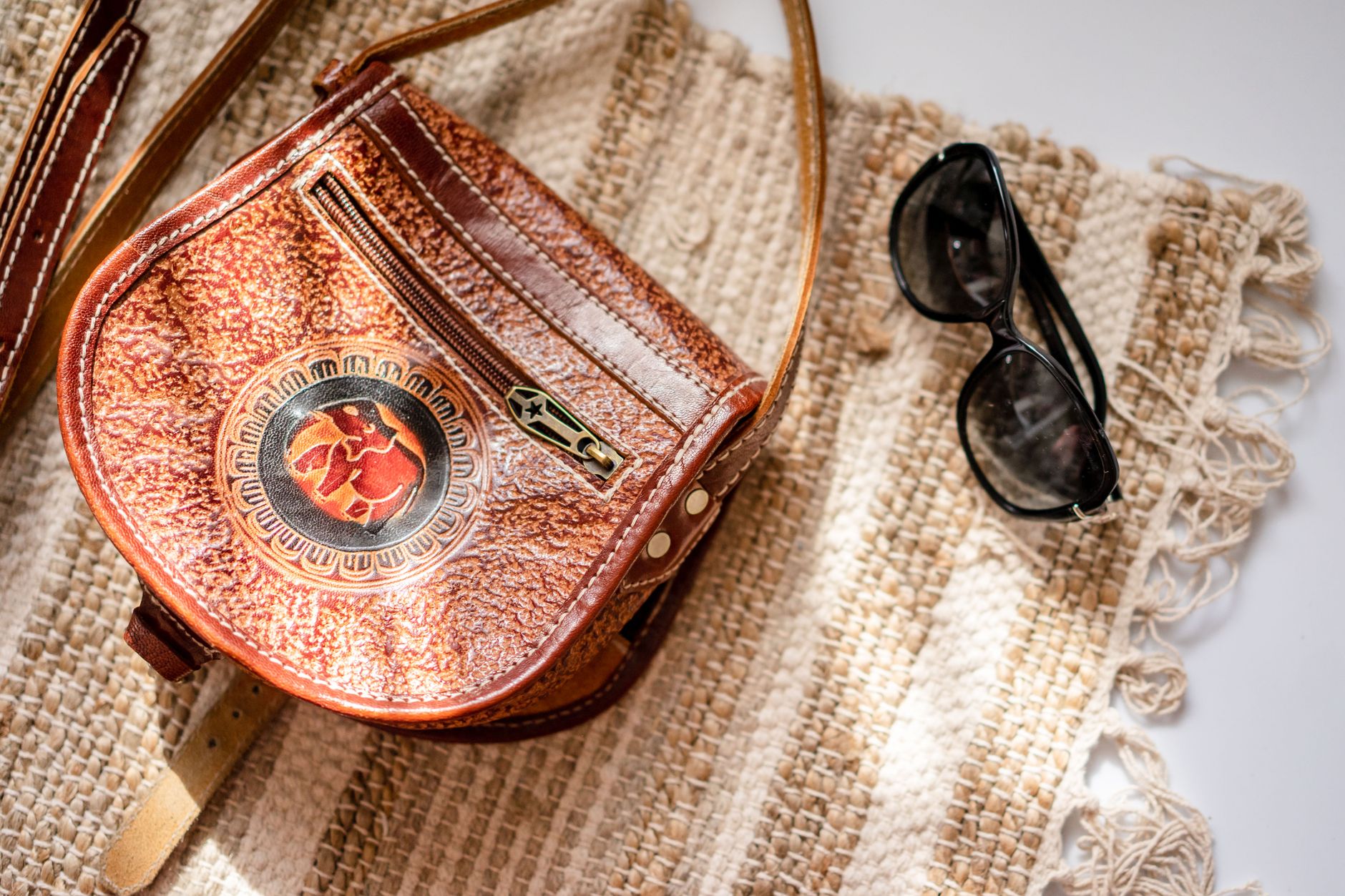 Sac à main et lunettes posés sur un tapis tressé