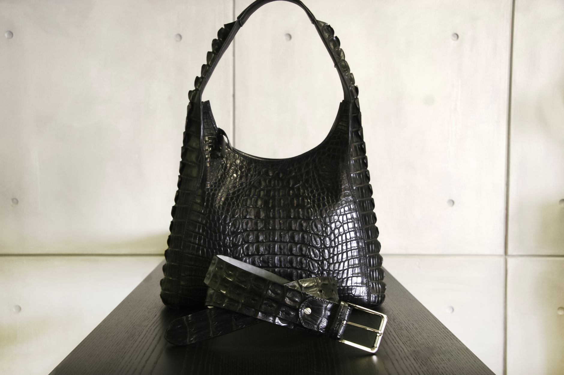 Sac noir en cuir façon crocodile posé sur un fond clair